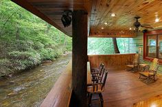 a covered porch with chairs and a river in the background