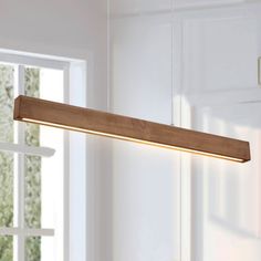 a wooden light fixture hanging from the ceiling in a room with white walls and windows