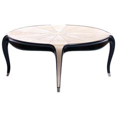 an oval table with black legs and a white flower design on the top, against a white background