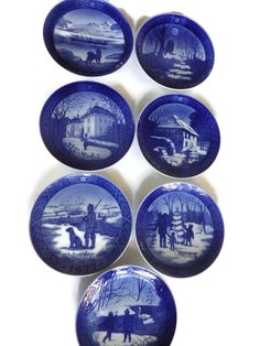 six blue and white plates with pictures of people in the snow, on top of each other