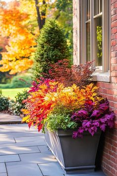 a planter filled with colorful flowers next to a brick building