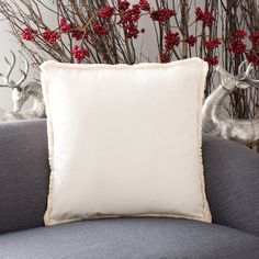 a white pillow sitting on top of a couch next to a vase with red flowers