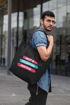 a man carrying a black tote bag that says not a morning person