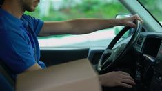 a man sitting in the driver's seat of a truck with his hand on the steering wheel