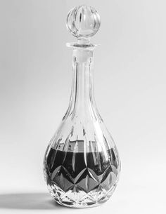 a clear glass decanter with a diamond design on the top and bottom, in front of a white background