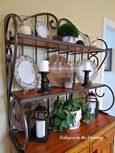 a shelf with plates and candles on it next to a wall mounted candle holder in the corner