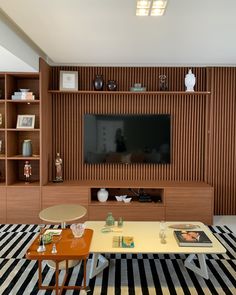 a living room filled with furniture and a flat screen tv mounted on a wooden wall