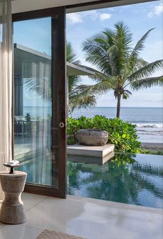 a living room filled with furniture next to a large glass door leading to the ocean