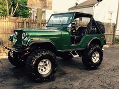 a green jeep parked in front of a house