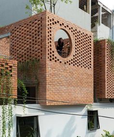 a brick building with a circular hole in the center and plants growing out of it