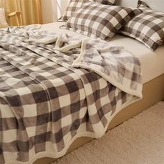 a bed with plaid sheets and pillows on top of it in a bedroom next to a window