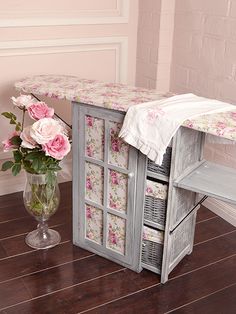 a vase filled with flowers sitting next to an ironing board on top of a wooden floor