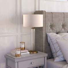 a nightstand with a lamp on it next to a bed