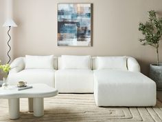 a living room with a large white couch and coffee table in front of a painting on the wall