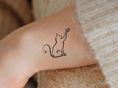 a cat tattoo on the arm of a woman's left arm, with a heart in it