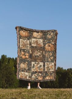 a person standing in front of a large quilt with pumpkins and leaves on it