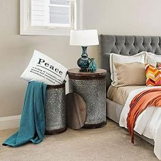 a bedroom with a bed, nightstands and pillows on the floor in front of a window