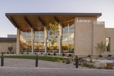 the library building has many windows on it's front and side walls, along with brick walkways