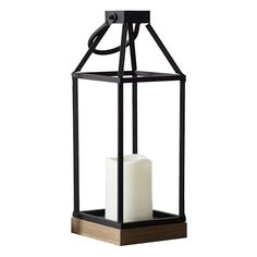 a black lantern with a white candle in it on a wooden block and metal frame