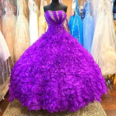 a purple ball gown sitting on top of a wooden floor in front of mannequins