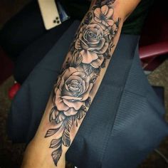 a woman's arm with flowers and leaves on it