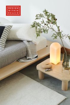 a bed sitting next to a table with a plant on it