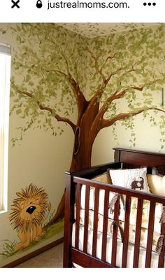 a baby's room with a tree painted on the wall and a crib