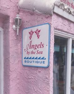 a sign on the side of a pink building that says angels by the sea boutique