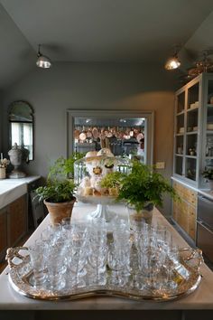 a table with many glasses on it and plants in the middle, along with other glassware