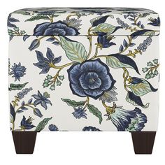 a blue and white flowered ottoman with wooden legs, on a white background that has leaves and flowers all over it