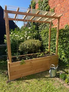 a wooden garden box with plants growing in it and a watering can next to it