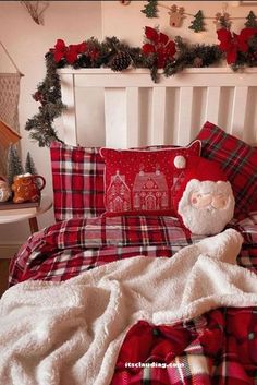 a bed covered in plaid sheets and blankets with a teddy bear on top of it