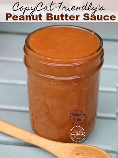 a wooden spoon sitting next to a jar of peanut butter sauce