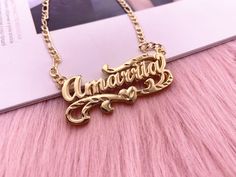 a gold necklace with the word anniversary on it sitting on top of a pink furry surface