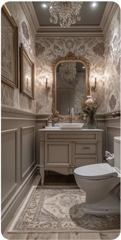 a bathroom with a toilet, mirror and chandelier on the wall above it