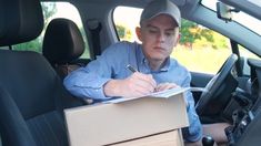 a man sitting in the back seat of a car writing on a piece of paper