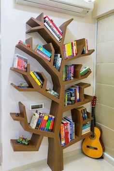 a tree shaped book shelf with books on it and a guitar in front of it