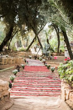 a red and white rug is on the ground next to some chairs in front of trees