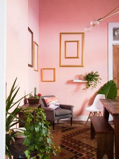 a living room with pink walls and wooden furniture in the corner, along with potted plants