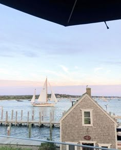 a sailboat is in the water next to a house with a boat on it