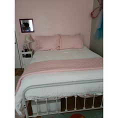 a white bed with pink sheets and pillows