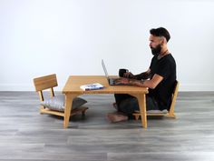 a man sitting at a table with a laptop on his lap and holding a coffee mug