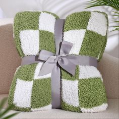 a green and white checkered pillow with a bow on it's side sitting on a couch