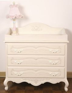 a white dresser with a pink lamp on top