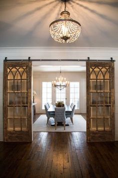 an open door leading to a dining room with chairs and a chandelier hanging from the ceiling