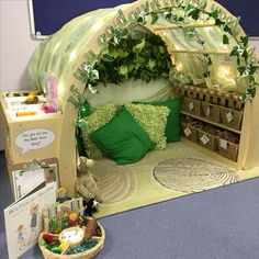 a bed made out of cardboard with lots of green decorations on it and a basket filled with toys