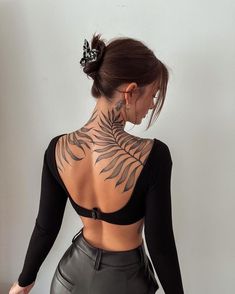 the back of a woman's body with tattoos on her upper and lower half