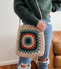 a woman is holding a crocheted bag in her hands and wearing ripped jeans