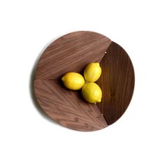 three lemons in a wooden bowl on a white surface