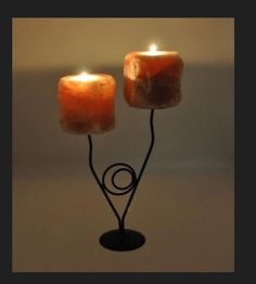 two lit candles sitting on top of a metal stand